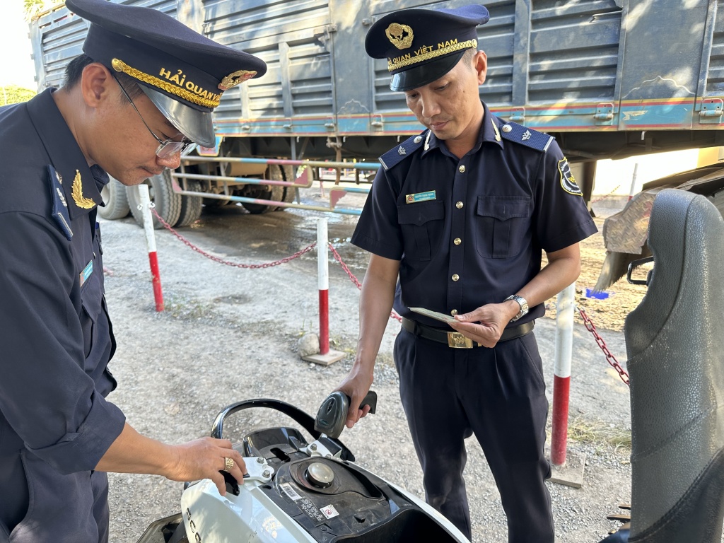 Anh Nguyễn Thanh Phong (bên phải) cùng đồng nghiệp kiểm tra phương tiện nhập cảnh bằng phần mề quét mã vạch. Ảnh: T.H