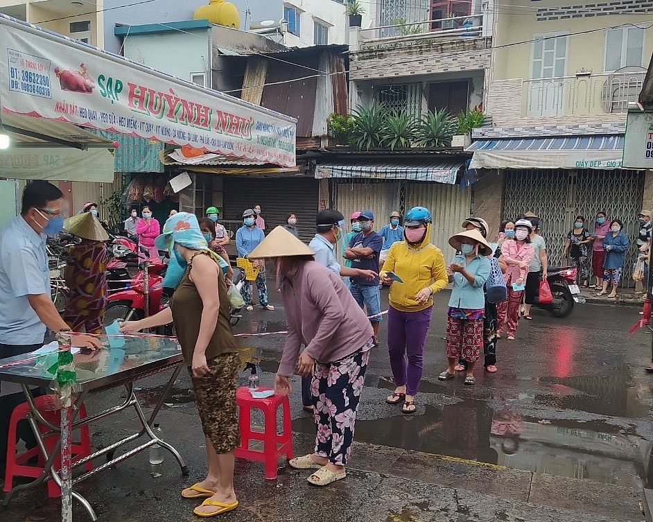 Người dân xếp hàng khử khuẩn, khai báo y tế trước khi vào chợ. Ảnh: HT