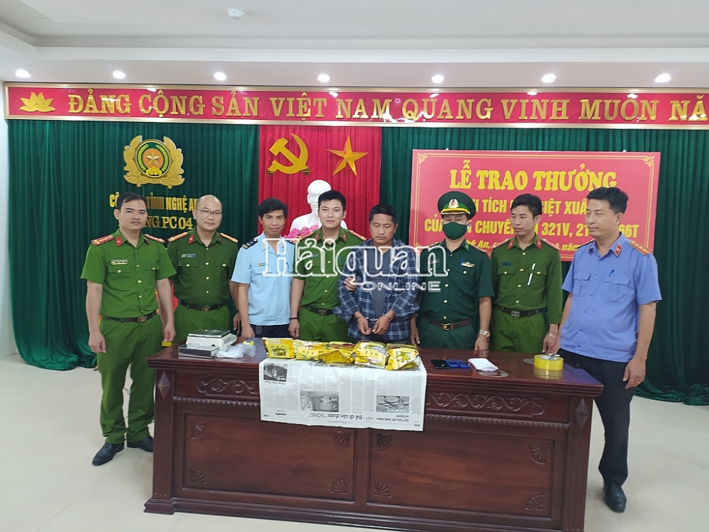 Đối tượng (mặc áo kẻ sọc) đứng giữa cùng tang vật bị bắt giữ. Ảnh: Tô Hiếu